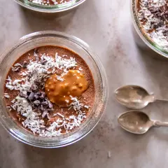 Chokladmousse med kokosflingor och kakaonibs, en härlig vegansk frukost. Två skedar ligger bredvid.