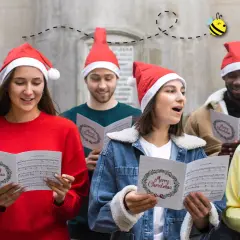Giovani con cappelli natalizi cantano "le più belle canzoni di natale in inglese" da spartiti con "Merry Christmas".