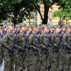 Żołnierze w mundurach polowych, z karabinami, maszerują w defiladzie. To widok z kategorii e wojsko, symbol dumy narodowej.