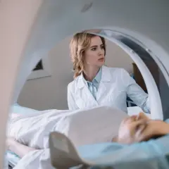 Lekarka nadzoruje badanie rezonans serca. Pacjent leży na stole aparatu MRI.