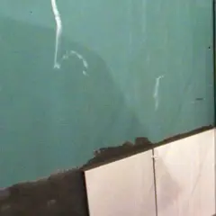 Angolo di una stanza con piastrelle su cartongesso in fase di posa. La parete verde è pronta per essere rivestita.