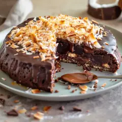 En saftig falsk toscakaka med chokladglasyr och rostad kokos. En sked med chokladsås ligger bredvid.