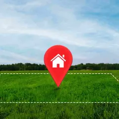 Un terreno verde con un marcador rojo de casa en el centro. Ideal para tu hipoteca para comprar terreno y construir tu hogar soñado.