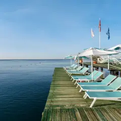 Leżaki i parasole na drewnianym molo nad spokojnym morzem, idealne miejsce na relaks w Limak Lara De Luxe.