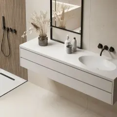 Installation lavabo moderne suspendu, avec robinetterie noire et miroir. Douche et murs texturés complètent l'ambiance.