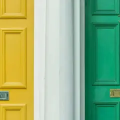 Dwie drzwi zewnętrzne, żółte i zielone, z numerami 31 i 33. Zastanawiasz się, czym pomalować drzwi zewnętrzne?