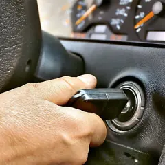 Dłoń przekręca kluczyk w stacyjce. Auto odpala i gaśnie, co sugeruje problem z zapłonem lub paliwem.