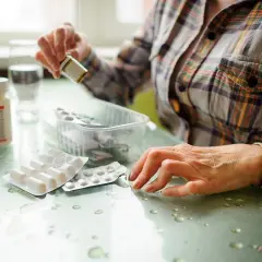 Kobieta przygotowuje się do leczenia biologicznego RZS, biorąc leki z opakowań.