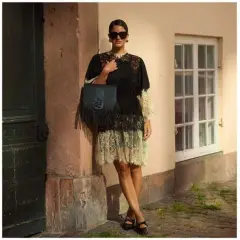 Estilo boho: mujer con collares dorados y top azul, otra con vestido de encaje negro y bolso flecos, y una tercera con vestido blanco volantes.