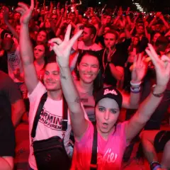 Tłum na koncercie Armin van Buuren Polska, fani pozdrawiają DJ-a, czerwone światła tworzą energetyczną atmosferę.