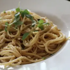 Deliciosa pasta con piñones y hierbas frescas, servida en un plato blanco.