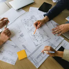 Manos revisando planos técnicos, un **informe pericial vivienda** en proceso.