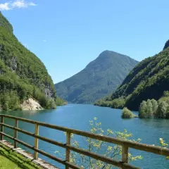 Il lago del Mis, incastonato tra montagne verdi e rigogliose, offre uno spettacolo mozzafiato con le sue acque azzurre e il cielo limpido.