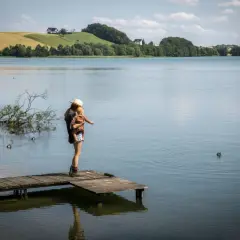 Kobieta z dzieckiem na rękach na pomoście, podziwia krajobraz. Sielski widok, jak ze szwajcarskiej wsi, ale to Kaszuby.