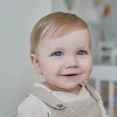 Un bébé aux yeux bleus pétillants sourit, prêt pour sa lettre demande de place en crèche urgent.