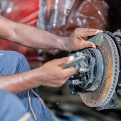 Mechanik wymienia klocki hamulcowe przy tarczy kotwicznej.