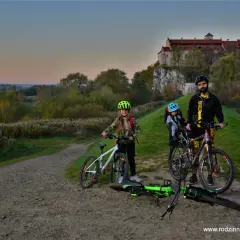Rodzina na rowerach pod zamkiem, odkrywają malownicze trasy rowerowe Małopolska.