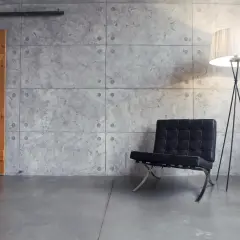 Drewniane drzwi przesuwne, czarne krzesło i lampa stojąca na tle betonowej ściany.