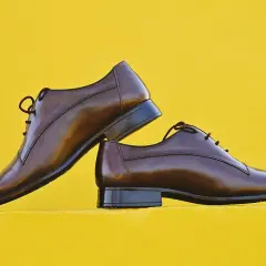Eleganckie, brązowe półbuty męskie na żółtym tle. Gotowe do wymiany fleków, by służyły latami.