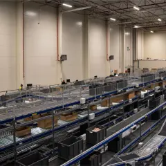 Nowoczesne centrum logistyczne z taśmociągami i pojemnikami, obsługujące usługi e-commerce.