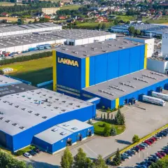 Widok z lotu ptaka na fabrykę Lakma z niebiesko-żółtymi budynkami i parkingiem.