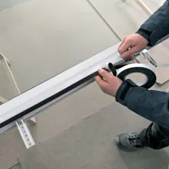 Pose porte fenêtre : application d'un joint d'étanchéité sur le cadre d'une fenêtre en aluminium.