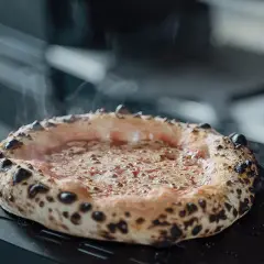 Frisch gebackene Pizza mit dampfendem Käse auf einem Pizzaschieber. Eine von vielen köstlichen Pizza sorten, bereit zum Servieren.