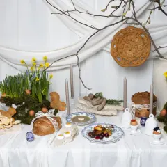 Wielkanocna oferta cateringowa: stół z tradycyjnymi potrawami, babkami, chlebem, jajkami i wiosennymi kwiatami.
