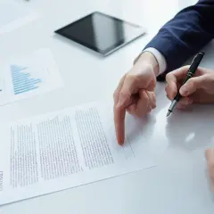 Dwie osoby omawiają umowę, analizując wykresy i dane. Kluczowa jest tu współpraca B2B.
