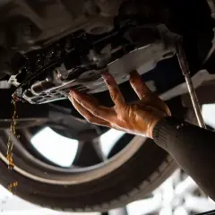 Mechanik spuszcza olej z miski olejowej. Dowiedz się, ile kosztuje wymiana oleju u mechanika.