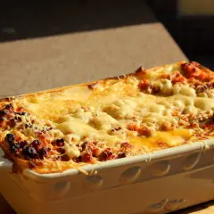 Gorąca, zapieczona lasagne orzepis w naczyniu, z ciągnącym się serem i rumianymi brzegami.
