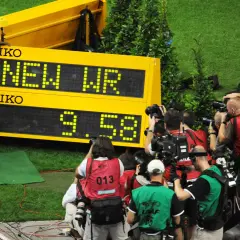 Usain Bolt, najszybszy człowiek świata, świętuje nowy rekord świata 9.58s. Otoczony przez fotoreporterów, z flagą Jamajki.