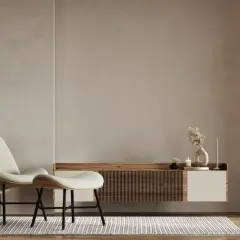A minimalist living room with a textured limewash wall, a modern chair and ottoman, and a floating media console.