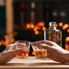 Dwie osoby wznoszą toast whisky. Zastanawiasz się, ile cukru jest w whisky?