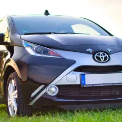 Czarny samochód Toyota z przodu, na tle trawy i nieba.