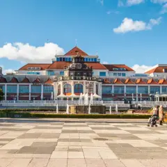 Sopot, część Trójmiasta, co to za miejsce? Plac z karuzelą i fontanną przed pięknym budynkiem.