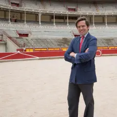 Eduardo Dávila Miura, con traje azul y corbata roja, posa en el ruedo de una plaza de toros.