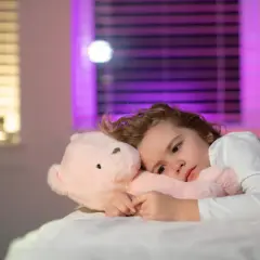 Smutne dziecko z pluszowym misiem, które nie może zasnąć. Bezsenność u dzieci to poważny problem.
