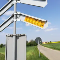 Znak informuje o numerze skrzyżowania i numerach alarmowych w razie wypadku lub awarii na przejeździe kolejowym.
