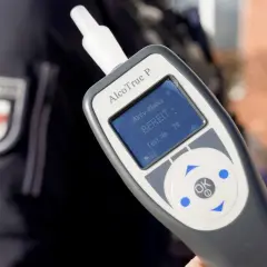 Polizist hält Alkoholtester. Das Gerät zeigt "BEREIT" an. Eine promille alkohol tabelle hilft, die Werte zu verstehen.