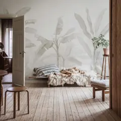 Salon w stylu boho z tapetą w liście bananowca, drewnianymi meblami i przytulnym legowiskiem.