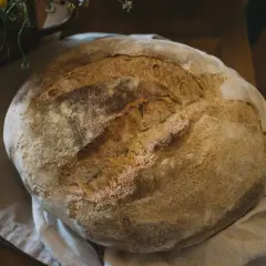 Świeżo upieczony, okrągły bochenek chleba na lnianej ściereczce.