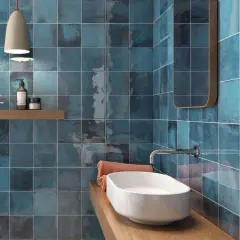 Bad fliesen ideen: glänzende, blaue Kacheln mit metallischem Schimmer, ein Waschbecken und ein Spiegel.