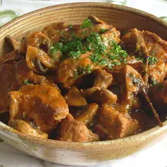 Un délicieux sauté de veau aux champignons, garni de persil frais, servi dans un bol en terre cuite.