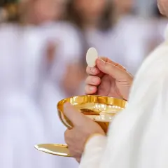 Ksiądz trzymający hostię i kielich podczas komunii świętej.