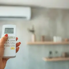 Main tenant ajuste la température de la climatisation pour un confort optimal, gérant la température clim été.