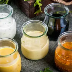 Fem burkar med olika dressingar, från krämig vit till mörk balsamico. Vilken är godaste dressingen till sallad?