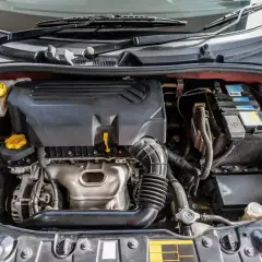 Silnik samochodu z widocznym zbiorniczkiem płynu chłodniczego. Gdzie jest czujnik temperatury w samochodzie? Zazwyczaj znajduje się w pobliżu termostatu lub w bloku silnika.