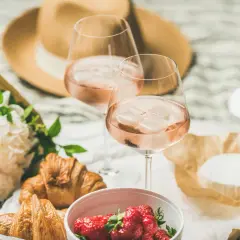 Zwei Gläser mit erfrischenden rose Weine, dazu Croissants, Erdbeeren und Käse. Ein perfektes Picknick!