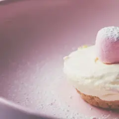 Delizioso namelaka al cioccolato bianco, con una soffice nuvola rosa in cima, adagiato su un piatto rosa cipria.
